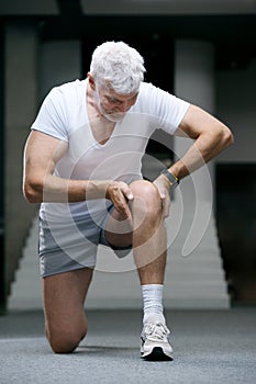 Gray haired senior injured knee or leg. Sport and health care concept
