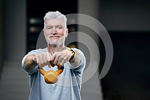 Gray haired senior man with kettlebell weight. Sport and health care concept