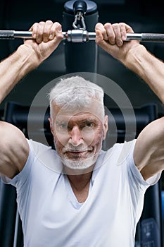 Gray haired senior man at machine gym. Sport and health care concept