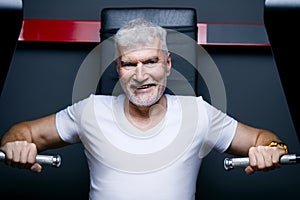 Gray haired senior man at machine gym. Sport and health care concept