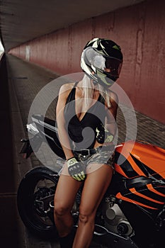 Gray haired sportswoman with helmet and orange motorcycle