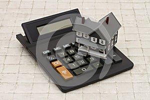 A gray house and calculator on stone background