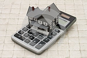 A gray house and calculator on stone background