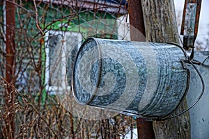 A gray iron bucket weighs on a wooden post