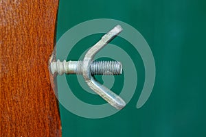Gray iron screw with nut in a brown wooden board