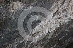 Gray karst cave. Rock formations in the cave, stalactites and stalagmites. Abstract gray grunge background. Stone texture