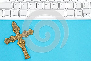 Gray keyboard with a religious cross on a blue paper