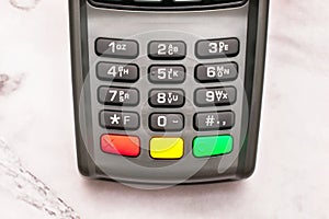 Gray keypad of contactless payment terminal standing on marble table, background, copy space