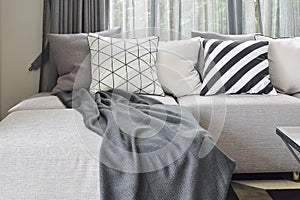 Gray L shape sofa with varies pattern and white pillows in