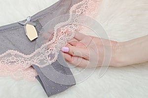 Gray lace panties in female hand. White background. Fashionable