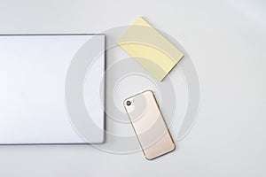 Gray laptop, a modern smartphone and a yellow journal isolated on a white background