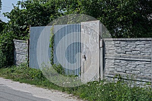 gray metal door and closed iron gate on a concrete fence