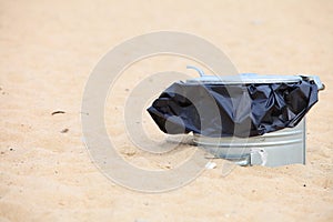 Gray metal garbage bin or can on beach