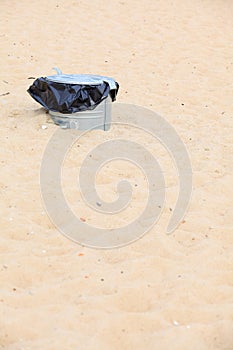 Gray metal garbage bin or can on beach