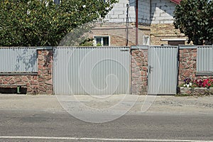 Gray metal gate and door and part of the wall of the fence