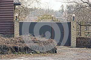Gray metal gates and a fence on the street overgrown with dry vegetation