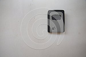 Gray metal key lock box securely fixed on a rough white wall background