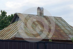 Gray metal roof of a rural house in brown rust