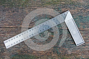 Gray metal square tool lies on a wooden board