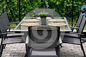 Gray metal table with 6 chairs outdoors in home garden.