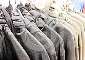 Gray and milky white roll-neck sweaters hanging on hangers in a clothing store