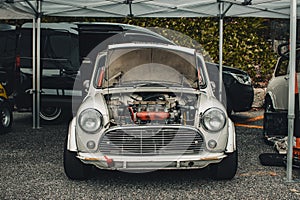 Gray mini cooper with open hood for engine repairs