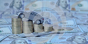 A gray model of a car with coins in the form of a histogram on a dollars background. Concept of lending, savings, insurance