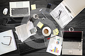 Gray office desk at a business meeting with laptops, phones and