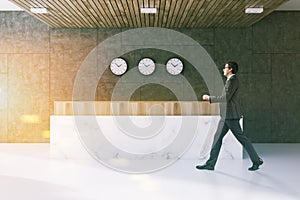 Gray office waiting room, reception, clocks, man