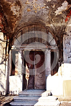 Gray old castle ruined walls and door with columns on sides, steps with bright sunlight