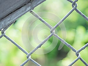 Gray paint on metal grille fence with de focused green nature background