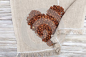 Gray peas scattered in form heart on wooden table with sackcloth. photo