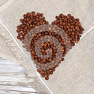 Gray peas scattered in form heart on wooden table with sackcloth.Traditional Latvian product photo