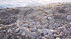 Gray pebbles on the beach at sunset sunrise. Sea shore. Ocean coast waves UHD