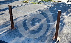 Gray pillars separating the park path from the road. deliberately rusty steel bollards bent into a double space slot connected by