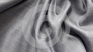 Gray plain weave suiting fabric with a sheen. The texture of the fabric.