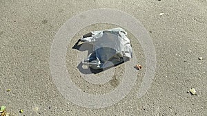 gray plastic bag lying on the street and moving in the wind.