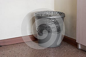Gray plastic waste paper basket transparent rubbish bag inside at the office corner