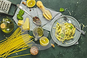 Gray plate of  Italian traditional perciatelli pasta by genovese pesto sauce served with ingredients on dark green concrete table
