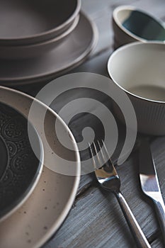 gray plates and bowls on white wooden table with cutlery