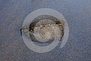 Gray pothole hole on the asphalt road