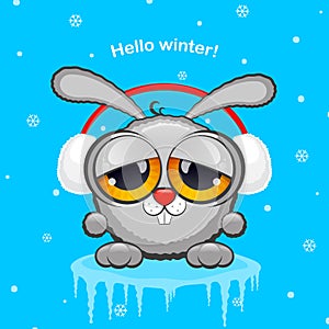 Gray rabbit in white fur headphones on a blue background with snow. The concept of winter, new year