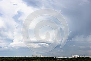 Gray rainy clouds with whirls over city and forest