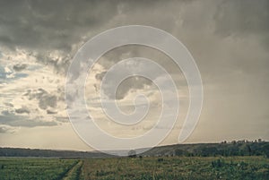 Gray rainy cloudy landscape over fields in the valley