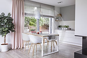 Gray roman shades and a pink curtain on big, glass windows in a