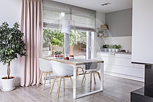 Gray roman shades and a pink curtain on big, glass windows in a photo