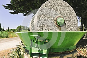 Gray rotating grinding wheel in a green, metal bucket