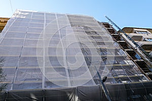 Gray safety net around a large city house facade during reconstruction, grey protective coating