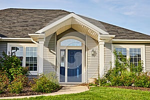 Gray siding house blue front door, arch entryway, slate gray checkered roof landscaping asset