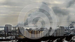 Gray smoke from the pipes metallurgical plant covers city buildings